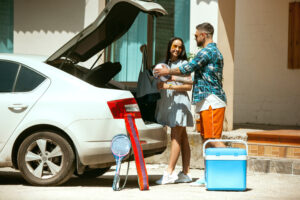 young couple preparing vacation trip car sunny day woman man stacking up sport equipment ready going sea riverside ocean concept relationship summer weekend